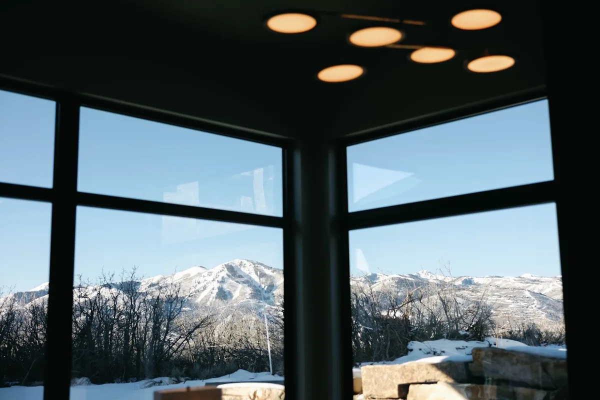 Great room at Skyridge with mitred corner glazing looking out to a snow-covered ridgeline