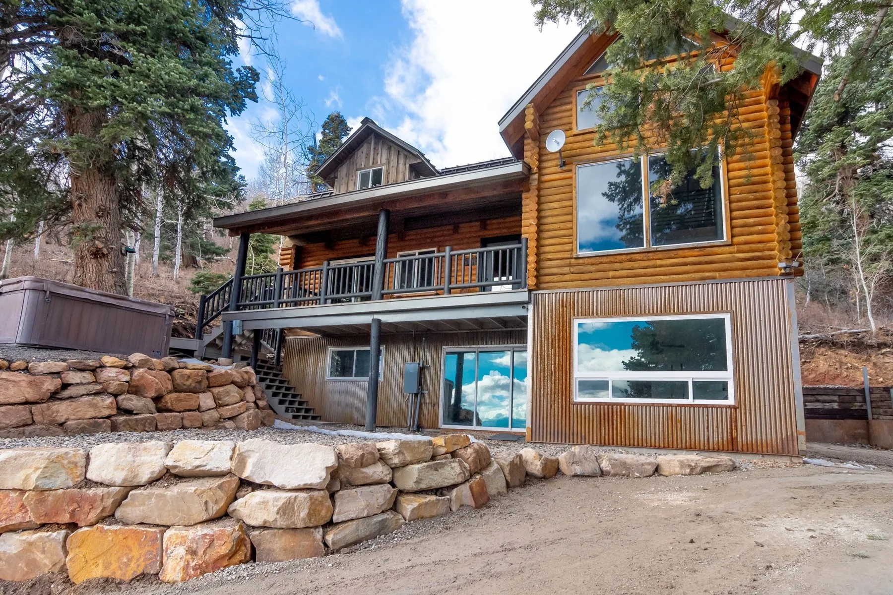 Remodelled log home exterior with a new deck, stone retaining wall and timber siding