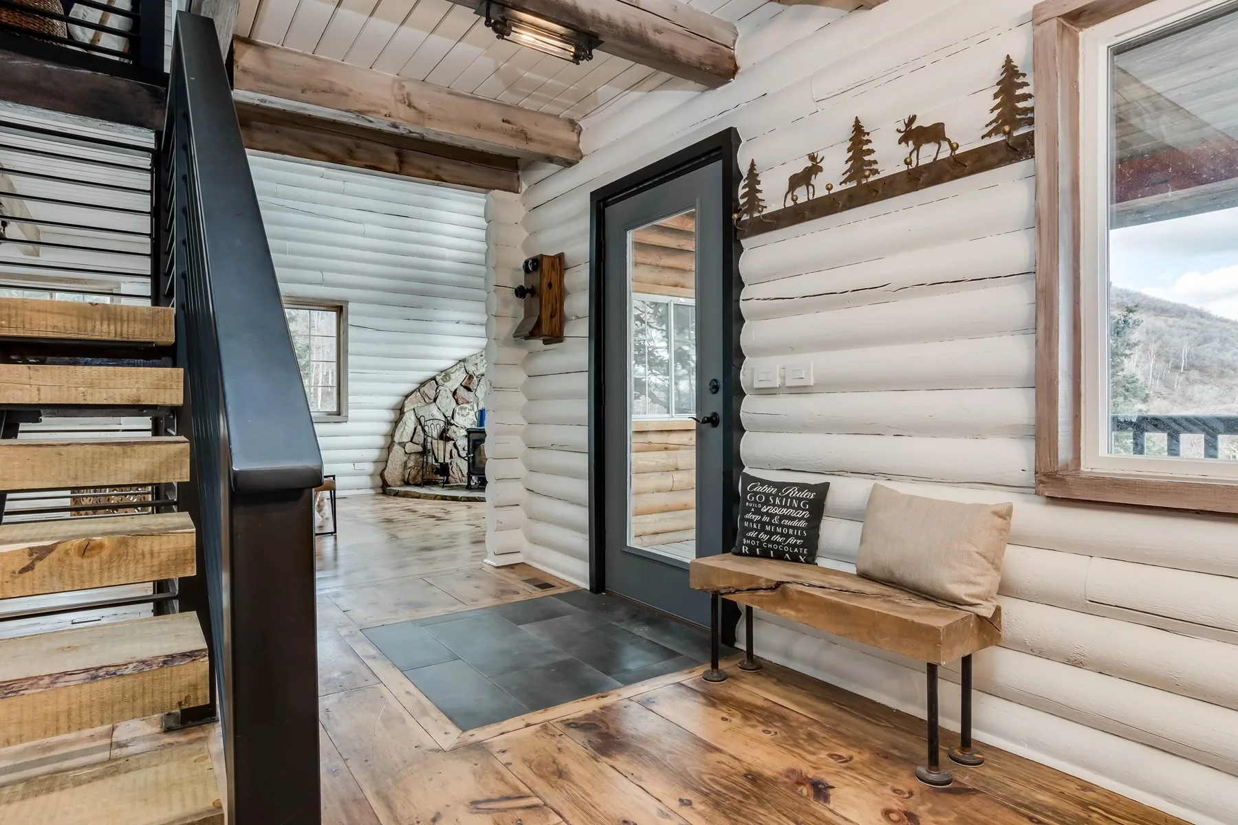 Open-riser steel and timber stair set against log walls at the Stagecoach remodel